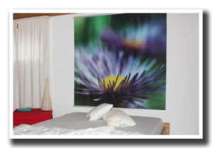 Großformatiges Blütenbild über einem Bett